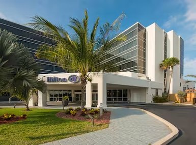 Das Hilton Hotel in Cocoa Beach präsentiert sich mit moderner Architektur und üppiger tropischer Vegetation im Vordergrund.