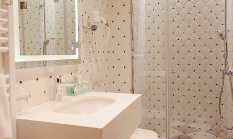 Ein modernes Badezimmer mit eleganter, weißer Einrichtung und einem großen Spiegel, der das Licht reflektiert.