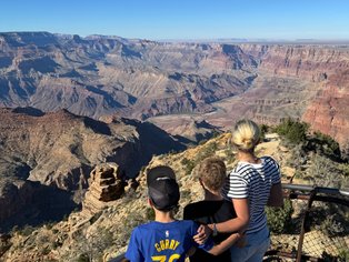 Drei Kinder stehen am Rand des Grand Canyon und bewundern die beeindruckende Aussicht auf die tiefen Schluchten und Felsen.