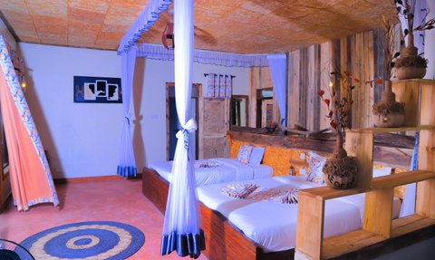 Ein gemütliches Zimmer mit zwei Betten, umgeben von rustikalen Holzwänden und dekorativen Pflanzen auf einem Regal.