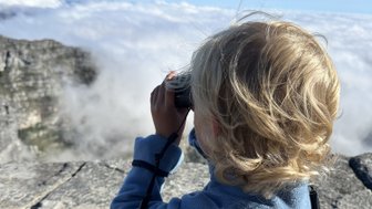 Junge schaut mit Fernglas über die Landschaft vom Tafelberg – Südafrika mit Kindern