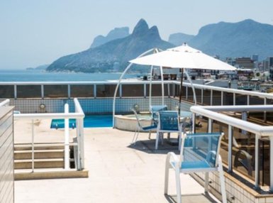Auf der Terrasse des Atlantis Copacabana Hotels steht ein kleiner Pool mit Blick auf die Küste und die umliegenden Berge.