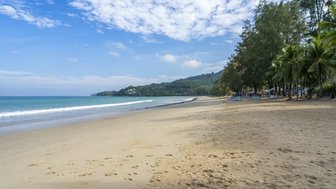 Ein ruhiger Strand mit feinem Sand, umgeben von Palmen und sanften Wellen, die an die Küste plätschern.