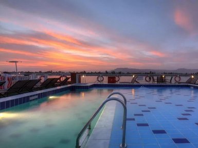 Die untergehende Sonne färbt den Himmel in warmen Tönen über einem beruhigenden Pool auf einem Schiff.