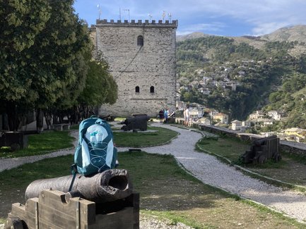 Eine steinerne Festung erhebt sich über eine grüne Landschaft, während Besucher den Weg entlang schlendern und die Aussicht genießen.