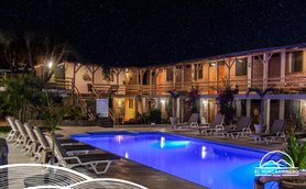 Ein einladender Hotelpool unter einem klaren Sternenhimmel, umgeben von gemütlichen Liegen und blühenden Pflanzen.