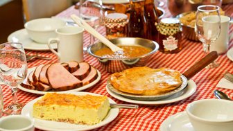 Ein gedeckter Tisch mit einer rot-weiß karierten Tischdecke, auf dem verschiedene köstliche Speisen angerichtet sind.