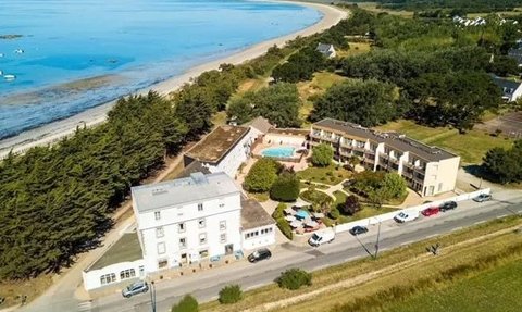 Ein Blick auf das Hotel de la Pointe de Mousterlin, umgeben von üppigem Grün und in der Nähe eines ruhigen Strandes.