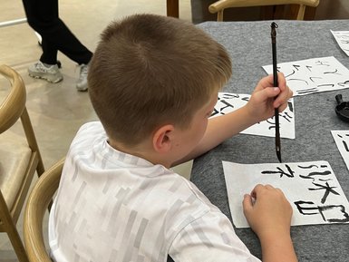 Kind schreibt chinesische Schriftzeichen bei einem Kalligrafie-Workshop – China Reise mit Kindern