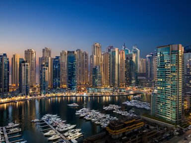 Die Skyline von Dubai bei Dämmerung, mit modernen Wolkenkratzern und einem ruhigen Yachthafen im Vordergrund.