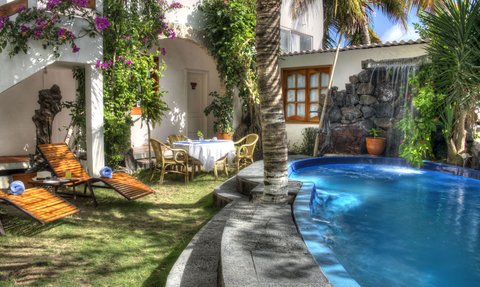 Ein einladender Poolbereich mit blühenden Pflanzen, Liegen und einem Tisch, ideal für entspannte Stunden im Freien.