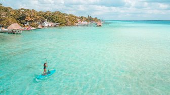 Teenagerin auf einem Paddleboard auf dem türkisfarbenen Wasser der Lagune von Bacalar – Mexiko mit Kindern