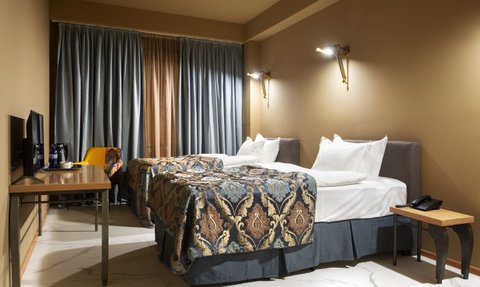 Ein elegantes Hotelzimmer mit zwei Betten, dekoriert mit opulenten Bettüberwürfen und sanften Beleuchtungselementen.