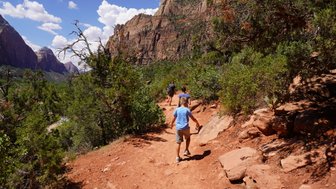 Eine Familie wandert auf einem schmalen Pfad durch die beeindruckende Landschaft des Zion-Nationalparks.