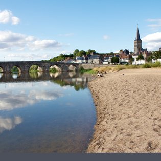 Ein ruhiger Strandabschnitt mit feinem Sand, der sanft ins Wasser übergeht, während Wolken sich im klaren Wasser spiegeln.