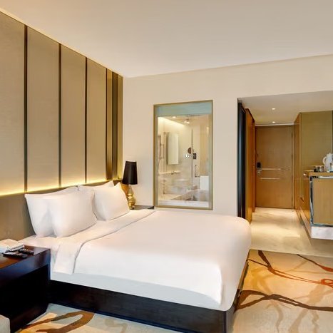 Ein modernes Hotelzimmer mit einem großen Bett, eleganten Möbeln und sanfter Beleuchtung, das Gemütlichkeit ausstrahlt.