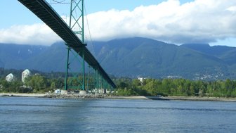 Die beeindruckende Hängebrücke erstreckt sich über das Wasser, umgeben von majestätischen Bergen und üppigem Grün.