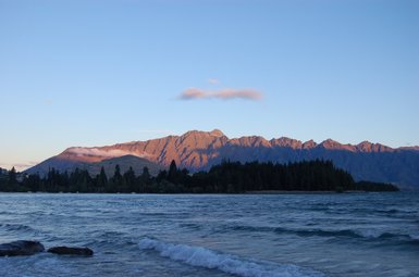 Der ruhige Lake Wakatipu spiegelt die majestätischen Berge im Hintergrund wider, während die Sonne sanft untergeht.