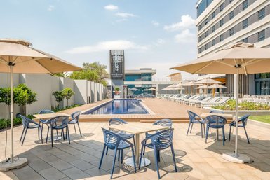 Ein eleganter Poolbereich im Radisson Hotel Johannesburg, umgeben von Sonnenschirmen und modernen Liegen.