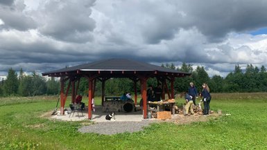 Eine Gruppe von Menschen versammelt sich unter einem Pavillon, während ein Hund entspannt auf dem Boden liegt.