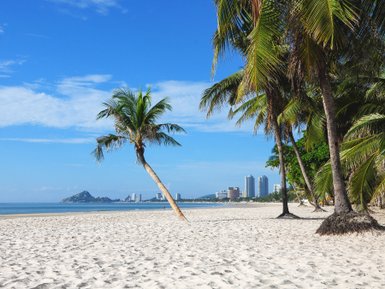Sandstrand, Meer und Palmen mit Blick auf die Stadt Hua Hin - Thailand mit Kindern