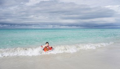 Ein Junge surft eine kleine Welle mit einem Bodyboard