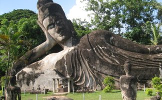 Eine massive, liegende Buddha-Statue dominiert den Park, umgeben von üppigem Grün und weiteren kleineren Statuen.