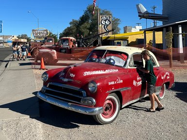 Ein roter Oldtimer steht in Seligman, Arizona, während ein Junge neugierig in das Auto schaut.