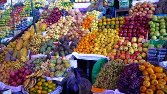 Ein lebhafter Marktstand voller frischer Früchte, darunter Äpfel, Bananen und Trauben, in bunten Farben angeordnet.