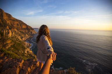 Frau steht am Aussichtspunkt am Chapman's Peak Drive und blickt auf den Ozean – Garden Route mit Kindern