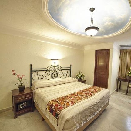 Ein elegantes Schlafzimmer mit einem großen Bett, dekoriert mit einer bunten Bettdecke und einem kunstvollen Deckenleuchter.