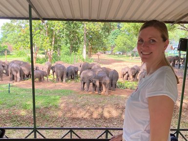 Frau steht vor dem Gehege mit Elefanten im Elephant Transit Home im Udawalawe Nationalpark – Sri Lanka mit Kindern