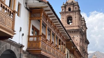 Die beeindruckende Architektur in Cusco zeigt kunstvoll geschnitzte Holzbalkone und eine majestätische Kirchturmstruktur.