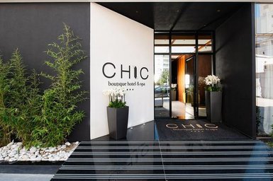 Der Eingangsbereich des Chic Boutique Hotels zeigt moderne Architektur mit eleganten Pflanzen und einem einladenden Ambiente.
