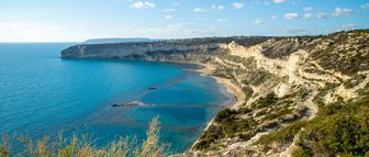 Eine atemberaubende Küstenlandschaft mit klarem, blauem Wasser und sanften Hügeln, die sich entlang der Küste erstrecken.
