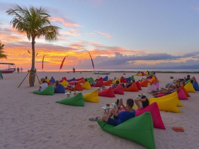 Bunte Sitzsäcke am Strand bieten eine entspannte Atmosphäre, während die Sonne hinter dem Horizont untergeht.