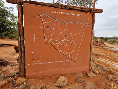 Eine detaillierte Karte des Tsavo Nationalparks East, die Straßen und Tierstandorte zeigt, auf einem lehmfarbenen Hintergrund.
