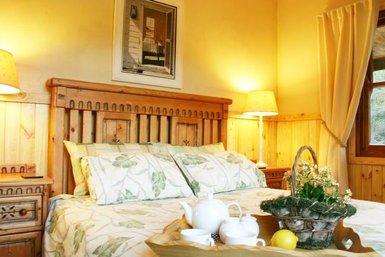 Ein gemütliches Schlafzimmer mit einem Holzbett, dekoriert mit blattförmigen Kissen und sanftem Licht von den Nachttischlampen.