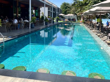 Ein einladender Poolbereich mit klarem Wasser, umgeben von modernen Liegen und schattenspendenden Sonnenschirmen.