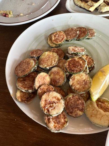 Ein Teller mit knusprig gebratenen Zucchinischeiben, die goldbraun und appetitlich angerichtet sind.
