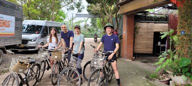 Eine Familie steht lächelnd vor ihren Fahrrädern in einer grünen Umgebung, bereit für eine Radtour durch die Natur.