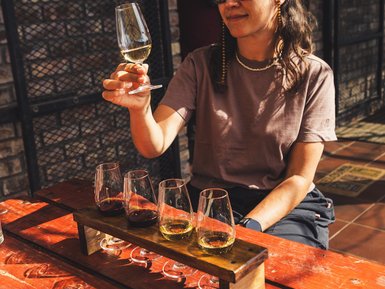 Frau probiert mehrere Weinsorten bei einer Weinverkostung – Südafrika mit Kindern