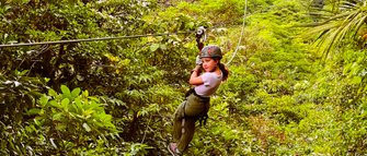Ein mutiges Mädchen gleitet an einer Zipline durch die Baumwipfel des Regenwaldes – Costa Rica Familienreise