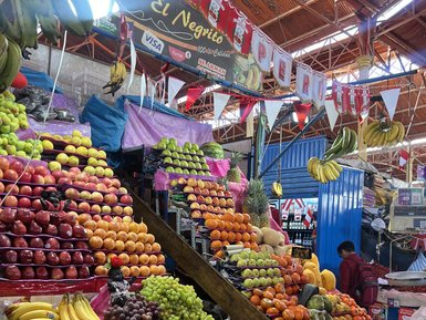 Bunte Obststände in einem Markt, mit einer Vielzahl von Früchten wie Äpfeln, Bananen und Trauben, die üppig präsentiert werden.
