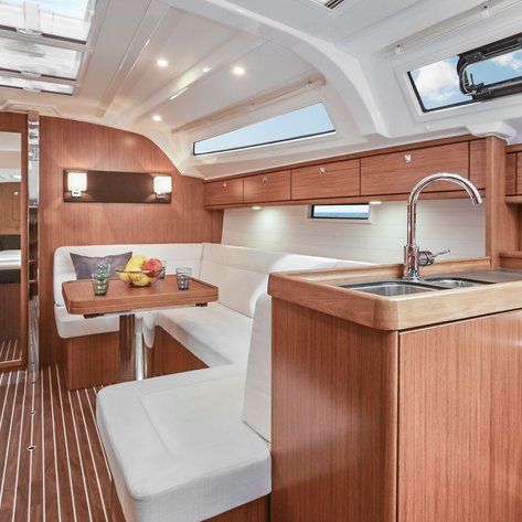 Der Innenraum einer modernen Yacht mit Holzverkleidung, einer gemütlichen Sitzecke und einer gut ausgestatteten Küche.