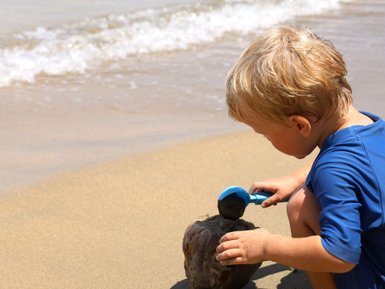 Kleines Kind spielt fröhlich im Sand am Strand – Costa Rica Familienreise