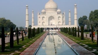 Das majestätische Taj Mahal erhebt sich über einen klaren Wasserkanal, umgeben von gepflegten Gärten und Besuchern.