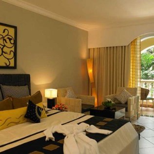 Ein elegantes Hotelzimmer mit einem großen Bett, stilvollen Möbeln und einem Fenster, das auf einen grünen Außenbereich blickt.