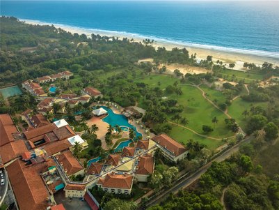 Ein atemberaubender Blick auf ein luxuriöses Resort mit Pools, umgeben von üppigem Grün und dem blauen Ozean im Hintergrund.