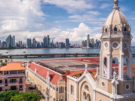 Die Skyline von Panama City erhebt sich majestätisch über das Wasser, umgeben von Wolken und strahlendem Himmel.